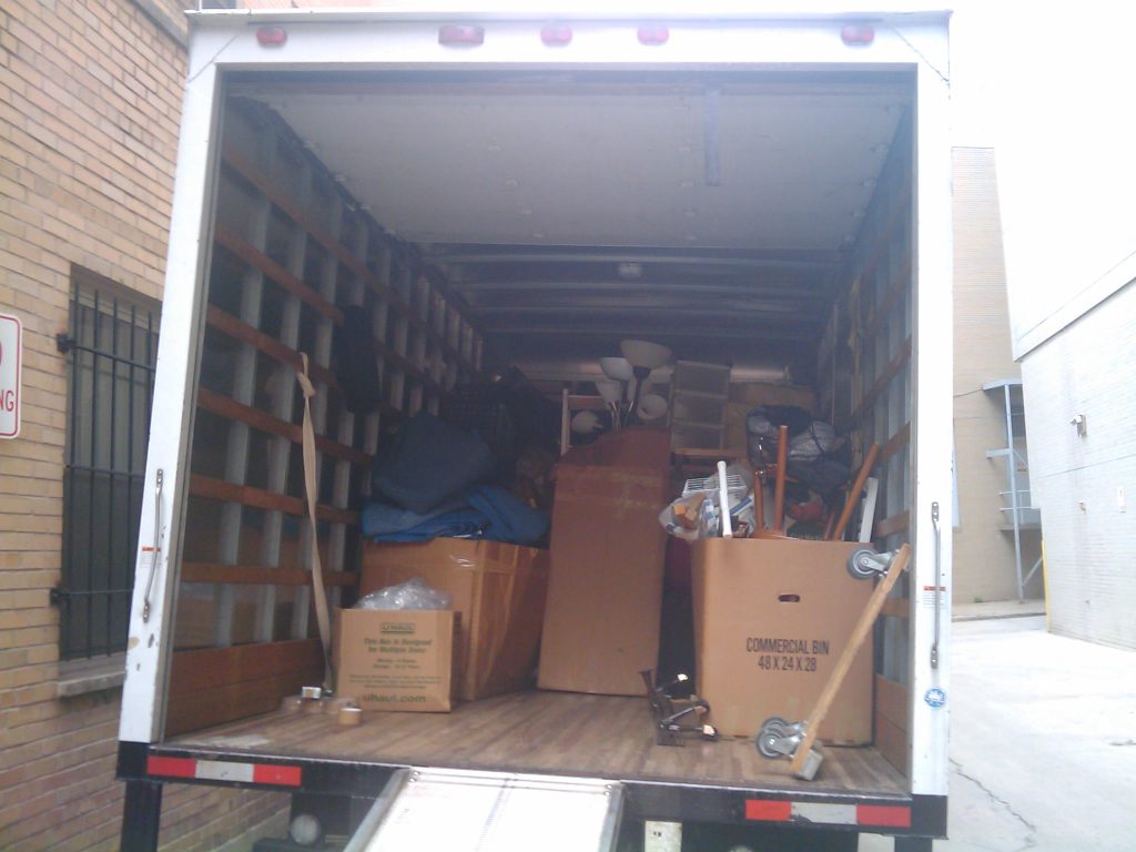 The open back of a moving truck, packed tight with boxes, lamps and furniture