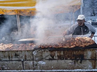 Jerk chicken quarters grilling over glowing coals with smoke rising